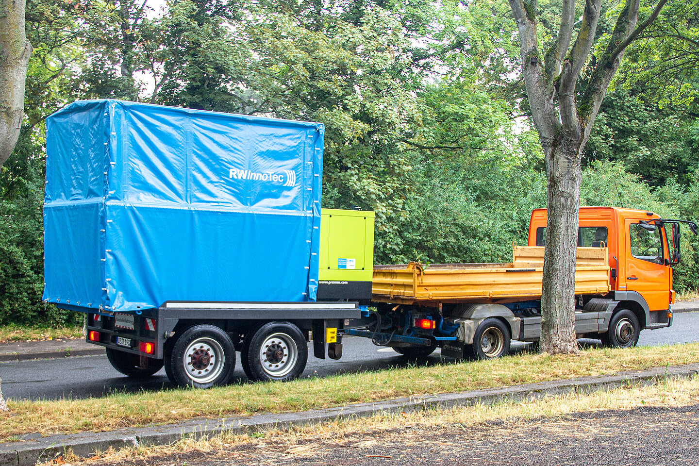 RWInnoTec‘s mobile Radiowellen-Anlage RWA-24/7 Ein LKW mit Anhänger. Unter der Anhänger-Plane befindet sich die mobile Radiowellen-Anlage von RWInnoTec, mit der das Unternehmen Schlaglöcher zügig, umweltfreundlich und rund um die Uhr sanieren kann.