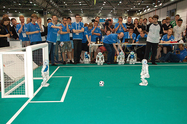 NAO-Roboter des gegnerischen Teams ist dabei, auf das Tor des HTWK Teams zu schießen