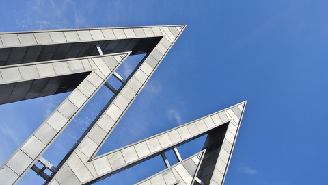 Illustration zum Fachgebiet: Metallenes Doppel-M als Symbol der Leipziger Mustermesse vor blauem Himmel