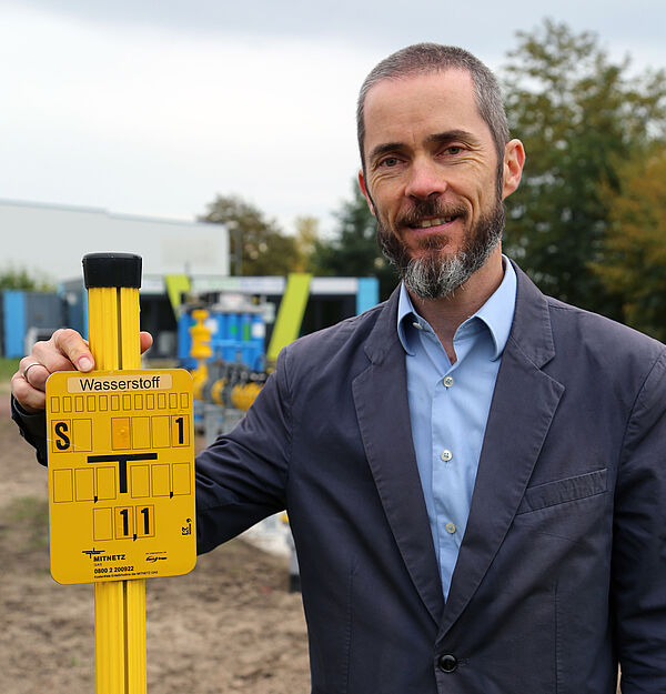 ein Mann steht nehem einem Gasschild mit der Aufschrift Wasserstoff