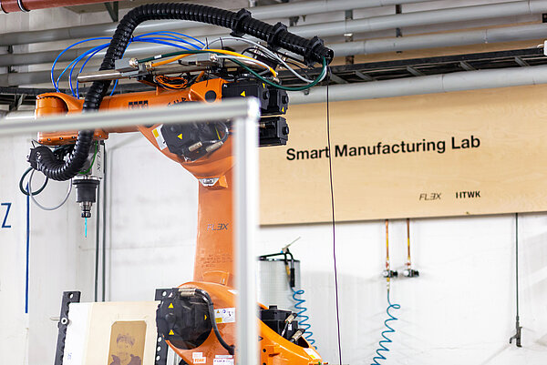 Smart Manufacturing Lab Blick in die Werkhalle auf den orangenen KUKA-Roboter