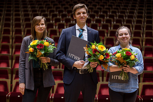 Zwei Frauen und ein Mann je mit Blumenstrauß in der Hand stehen auf der Bühne im großen Saal des Gewandhauses