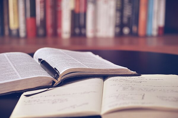 Ein Buch und ein Notizheft liegen versetzt aufeinander