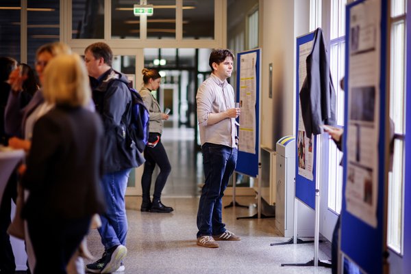 Interessierte schauen sich vor Veranstaltungsbeginn die Poster der Nominierten des Lehrpreises zu ihren Lehrkonzeptenan. 