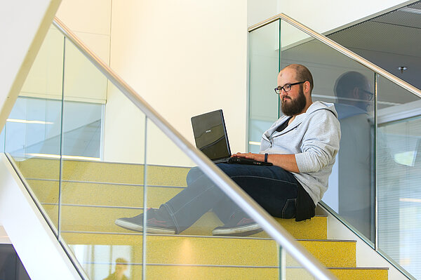 (Foto: Swen Reichhold/HTWK Leipzig) Student mti Laptop sitzt auf gelber Treppe