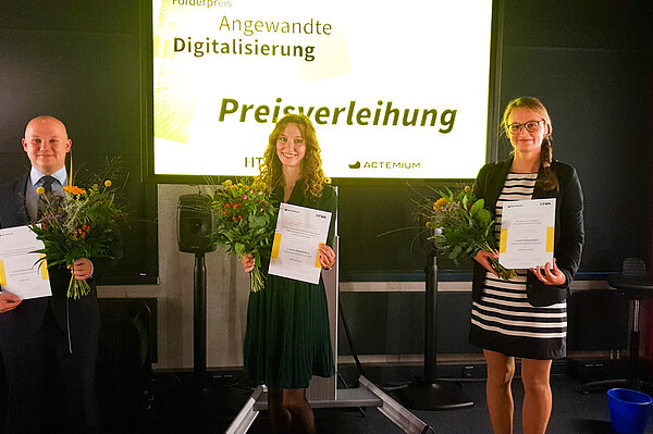 Helge Nickel, Stefanie Penzel und Zsófia Harsányi. (v.l.n.r.; Foto: Actemium) Ein Mann und zwei Frauen auf einer Bühne, sie erhalten Preise.