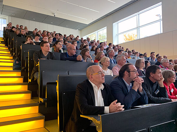 vollbesetzer Hörsaal mit gelben Treppen