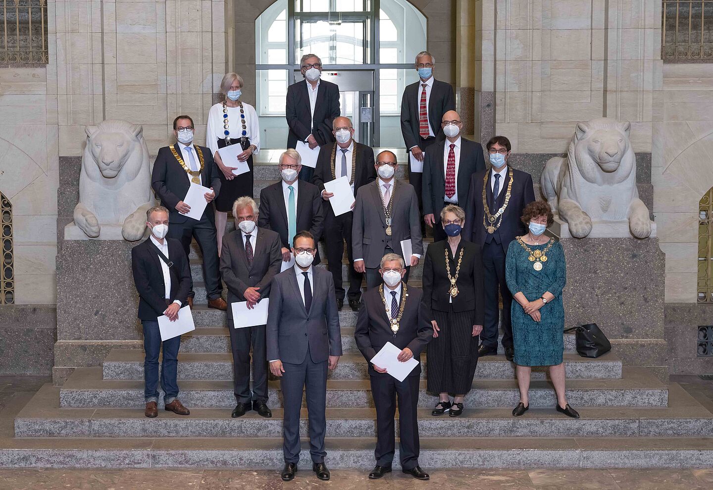 Viele Personen stehen gestaffelt auf einer Freitreppe vor einem Gebäude