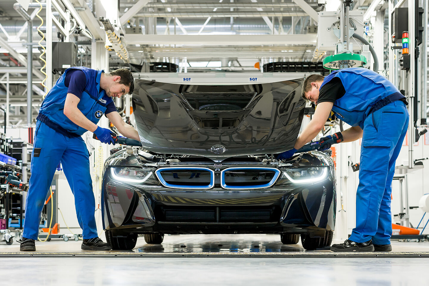 Im Leipziger BMW-Werk Zwei Mitarbeiter des Leipziger BMW-Werks montieren die Motorhaube an einen Sportwagen. Dabei nutzt der linke Mitarbeiter einen etwas ergonomischeren Bewegungsablauf als der rechte