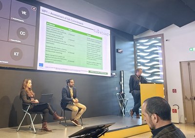 EU-Projekt EuReComp endet Prof. Böhm steht auf der Bühne und hält einen Vortrag. Neben ihm auf der Bühne sitzen zwei Menschen auf einem Stuhl