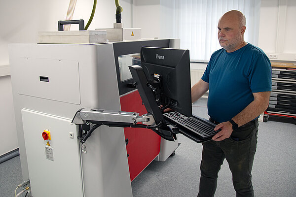 ein Mann schaut aufs Bedienfeld einen Druckers