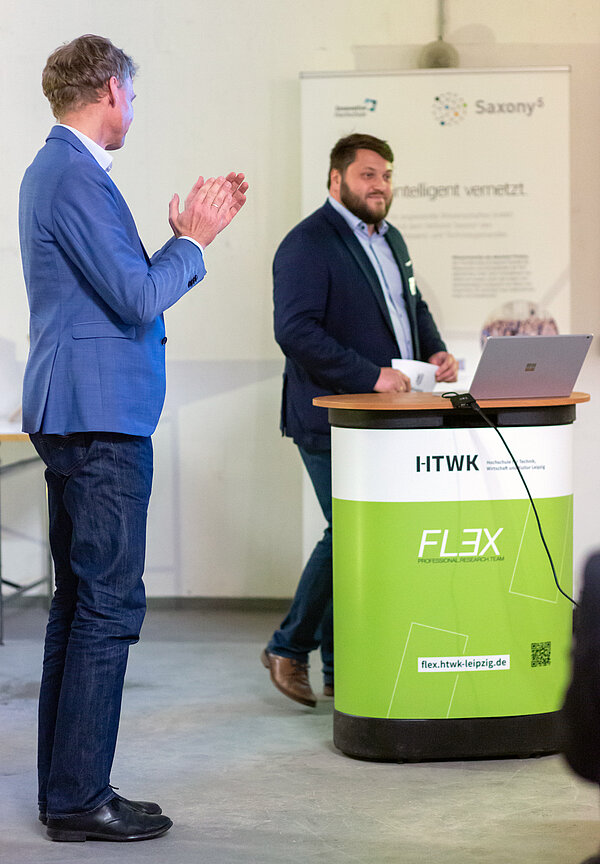 Rede Dr. Hans-Martin Dörfler Dr. Hans-Martin Dörfler steht am Rednerpult und Prof. Alexander Stahr applaudiert