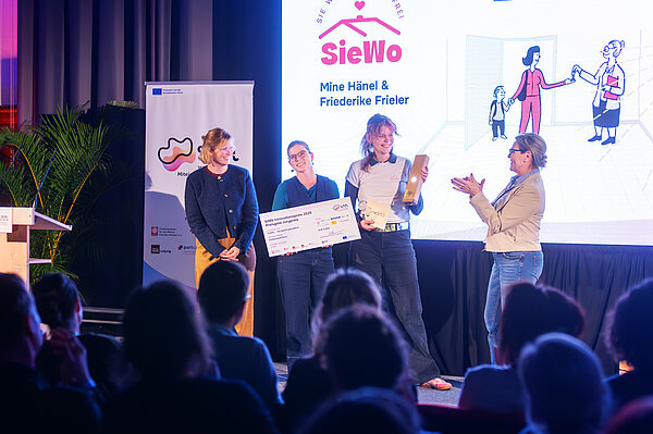 SieWo Bei der Preisverleihung nehmen 2 Frauen den Preis entgegen, 2 weitere Frauen stehen auf der Bühne und gratulieren