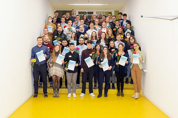 Gruppenbild der freudestrahlenden geförderten Studierenden mit Ukrunde und Blume in den Händen.