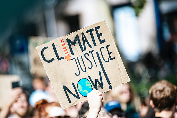 Eine Person trägt auf einer Demonstration ein Plakat mit dem Schriftzug "Climate Justice Now!"