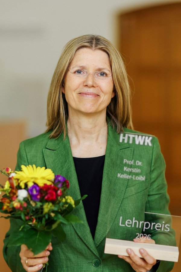 Professorin Keller-Loibl schaut sichtlich begeistert und zufrieden in die Kamera und präsentiert stolz ihre Trophäe.