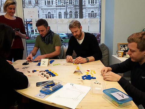 Workshop der LEAN Management Hochschulgruppe Eine Gruppe von Studierenden sitzt an einem Tisch und baut Lego zusammen.