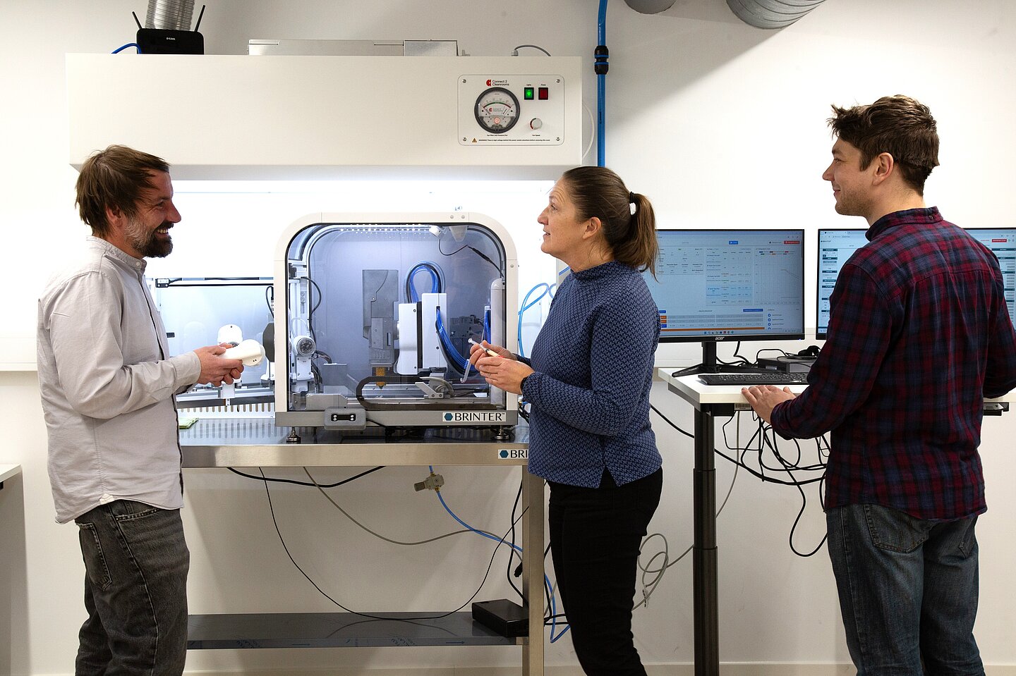 Drei Personen stehen am 3D-Drucker