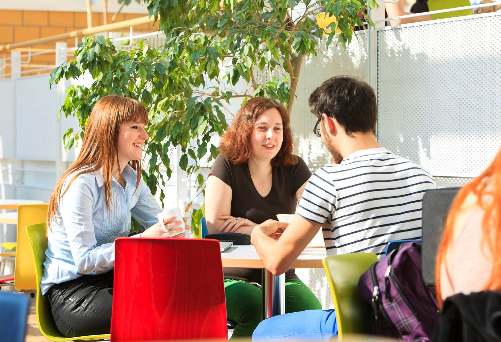 Drei Studierende stizen in der Mensa der HTWK an einem Tisch.