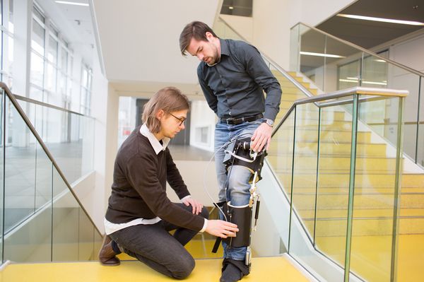 Max hat Exoskelett Prototyp am linken Bein, Felix justiert daran/Verlinkung führt zur Projektwebsite