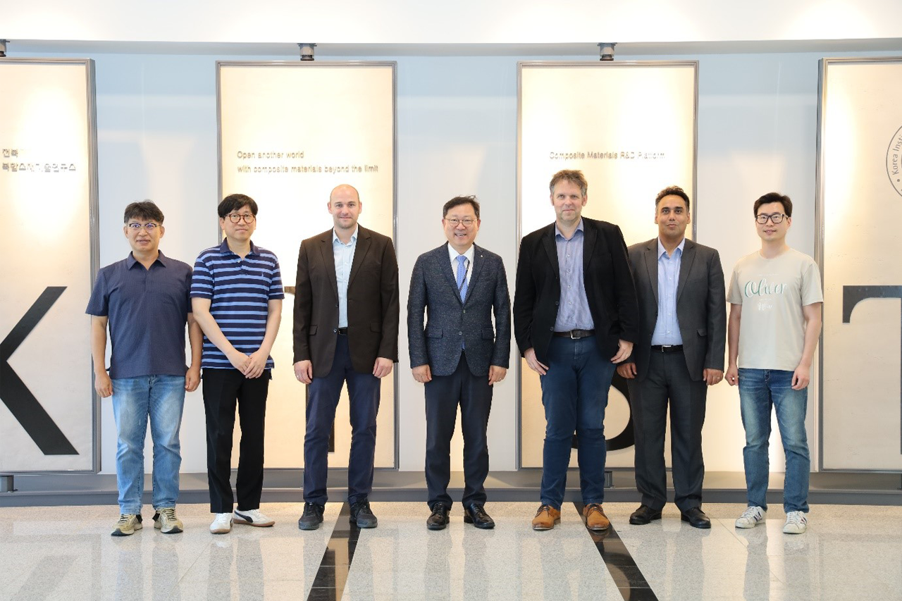 Gruppenfoto von Prof. Böhm und seinem Team mit Wissenschaftlerinnen und Wissenschaftlern, alle lächeln in die Kamera, Innenaufnahme, Logo des KIST im Hintergrund