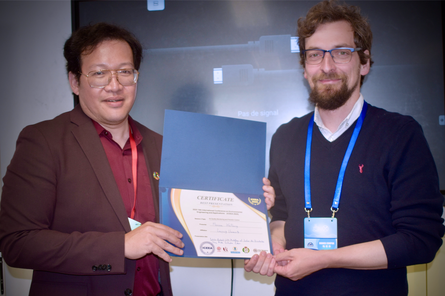 Beide Personen schauen in die Kamera und halten gemeinsam ein Zertifikat in der Hand