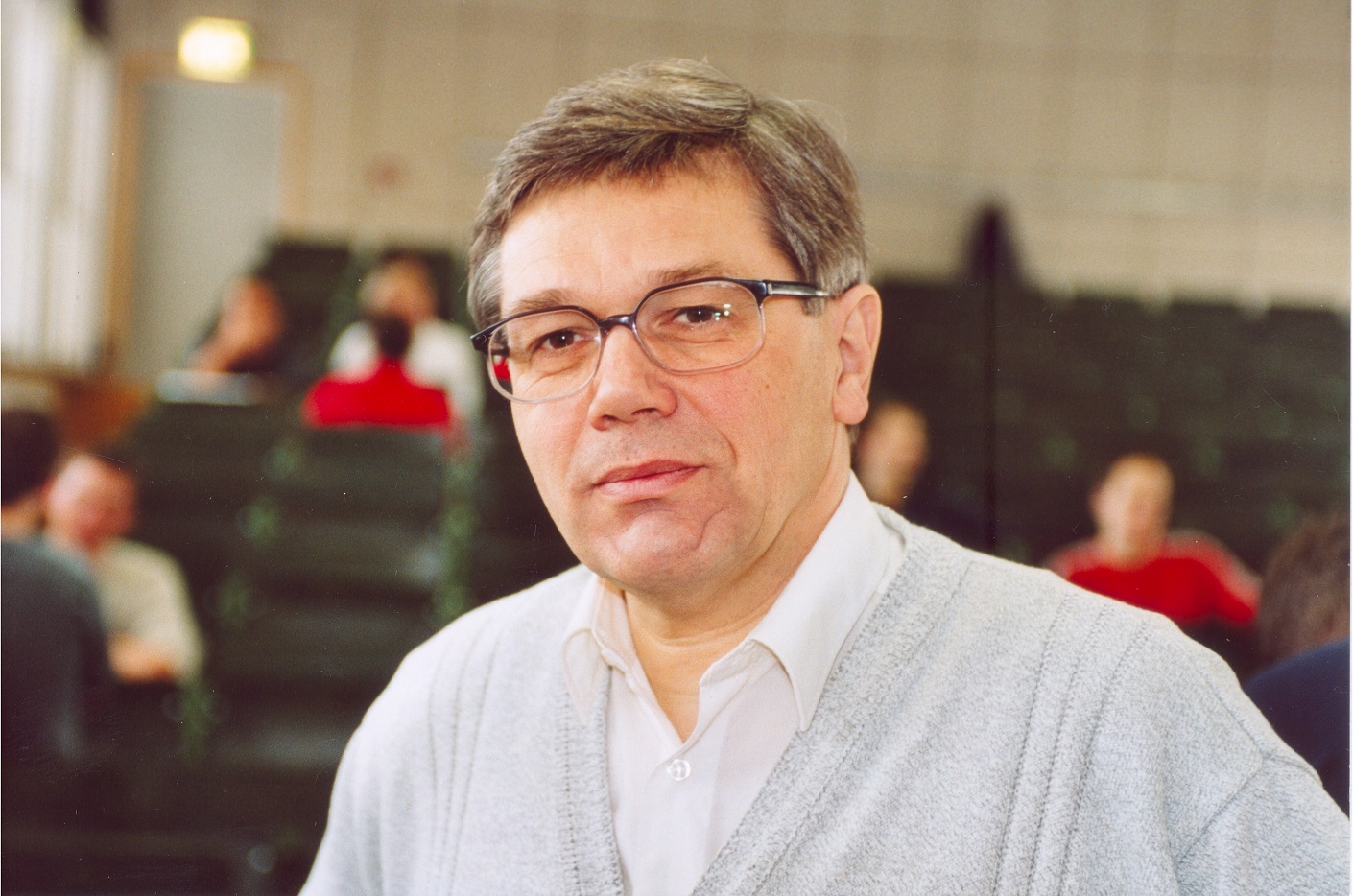 Portraitfoto Mann, im Hintergrund Hörsaalbänke